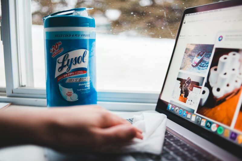 Person cleaning a computer using a disinfectant